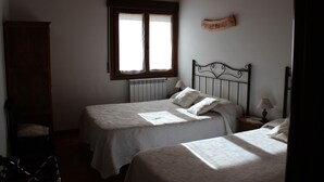 Un dormitorio con dos camas, una ventana, un armario de madera y un cartel en la pared.