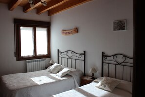 A bedroom with two beds, a window, a radiator, and a wall-mounted sign.