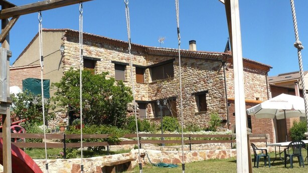A stone building with a swing set and a slide in the foreground.