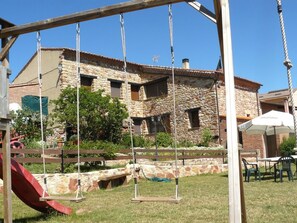 Un edificio de piedra con un columpio y un tobogán al frente.