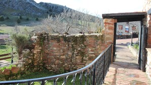 A stone wall with a metal railing, a brick pathway, and a building in the background.