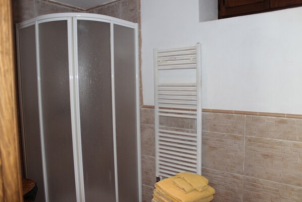 Un baño con cabina de ducha, toallero y pared revestida de azulejos.