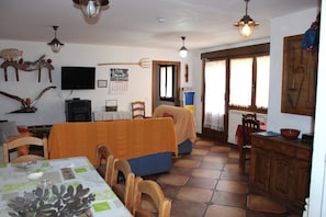 Un coin repas avec une table dressée pour deux personnes, un téléviseur fixé au mur et un calendrier.