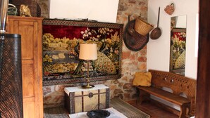 A room with a wooden bench, a patterned tapestry, a lamp, a wicker basket, and a stone wall.
