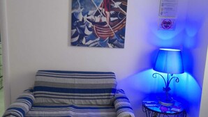 Une pièce avec un canapé à rayures, une table avec une lampe et un tableau au mur.