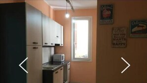 Une cuisine de taille réduite, équipée de placards, d’un four à micro-ondes et d’une fenêtre.