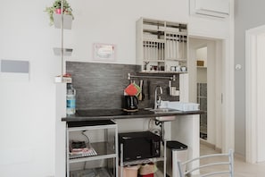 Cocina compacta con microondas, fregadero y estantes para guardar objetos.