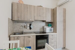 Eine kleine Küche mit Holzausstattung, einem Backofen, einer Mikrowelle und einem Spülbecken.