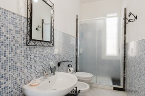 A bathroom with a white sink, toilet, and glass shower enclosure.