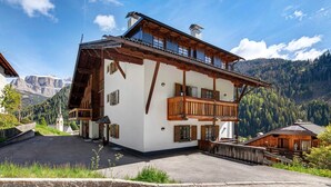 Ein zweistöckiges Gebäude mit Balkon, einem kleinen Anbau und einem Berg im Hintergrund.