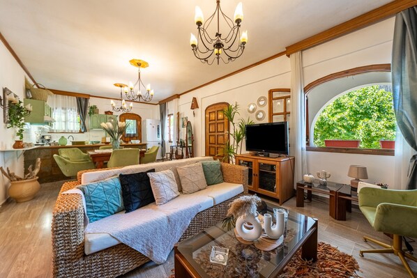 A cozy living room with a sofa, television, and dining area.