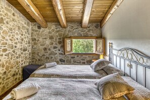Ein Schlafzimmer mit Stehwänden und Holzboden, zwei Betten, einem Fenster mit Blick und einem Metall-Kopfteil.