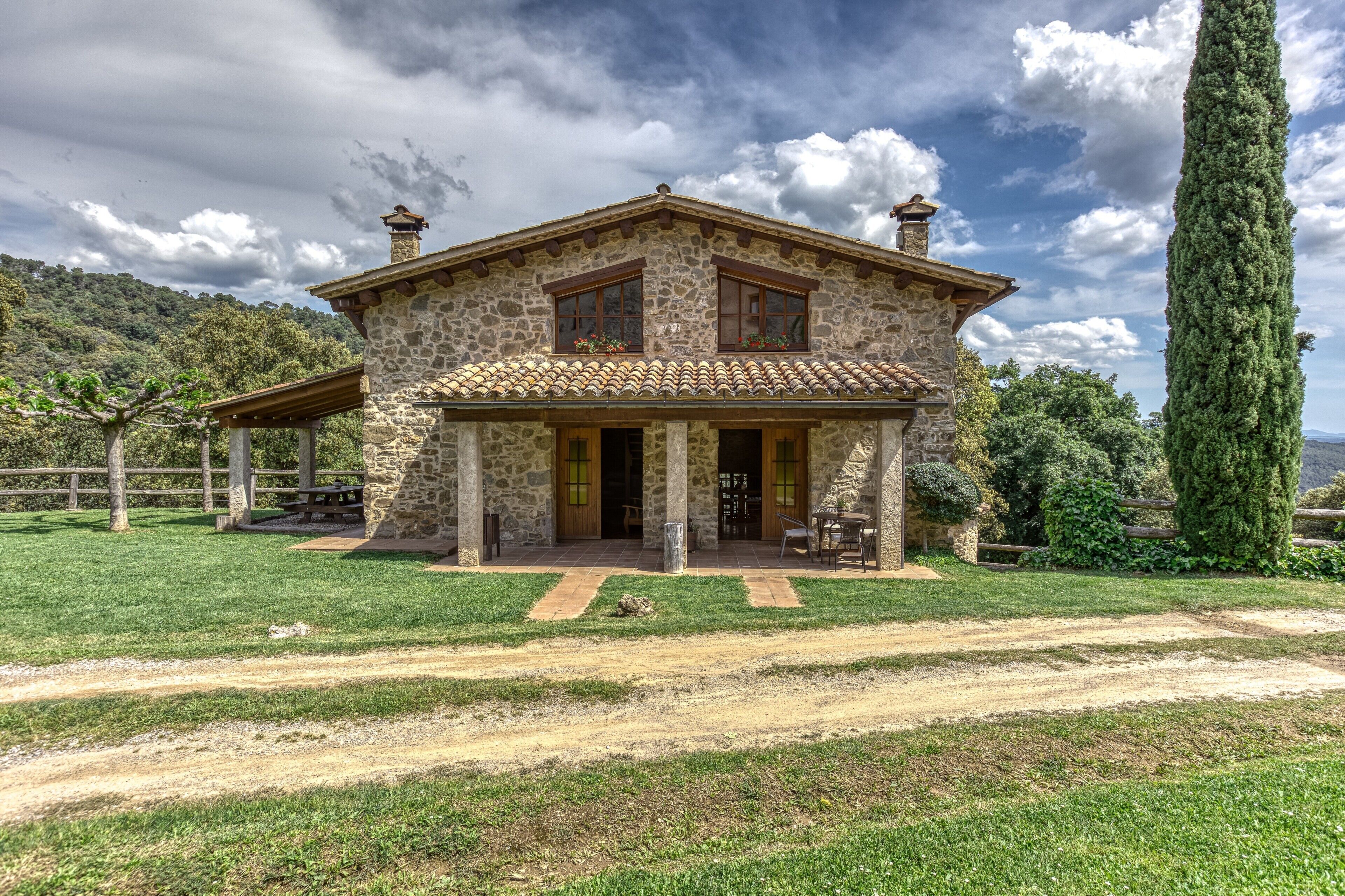 Una casa de piedra con techo de tejas, un porche cubierto y un césped bien cuidado.