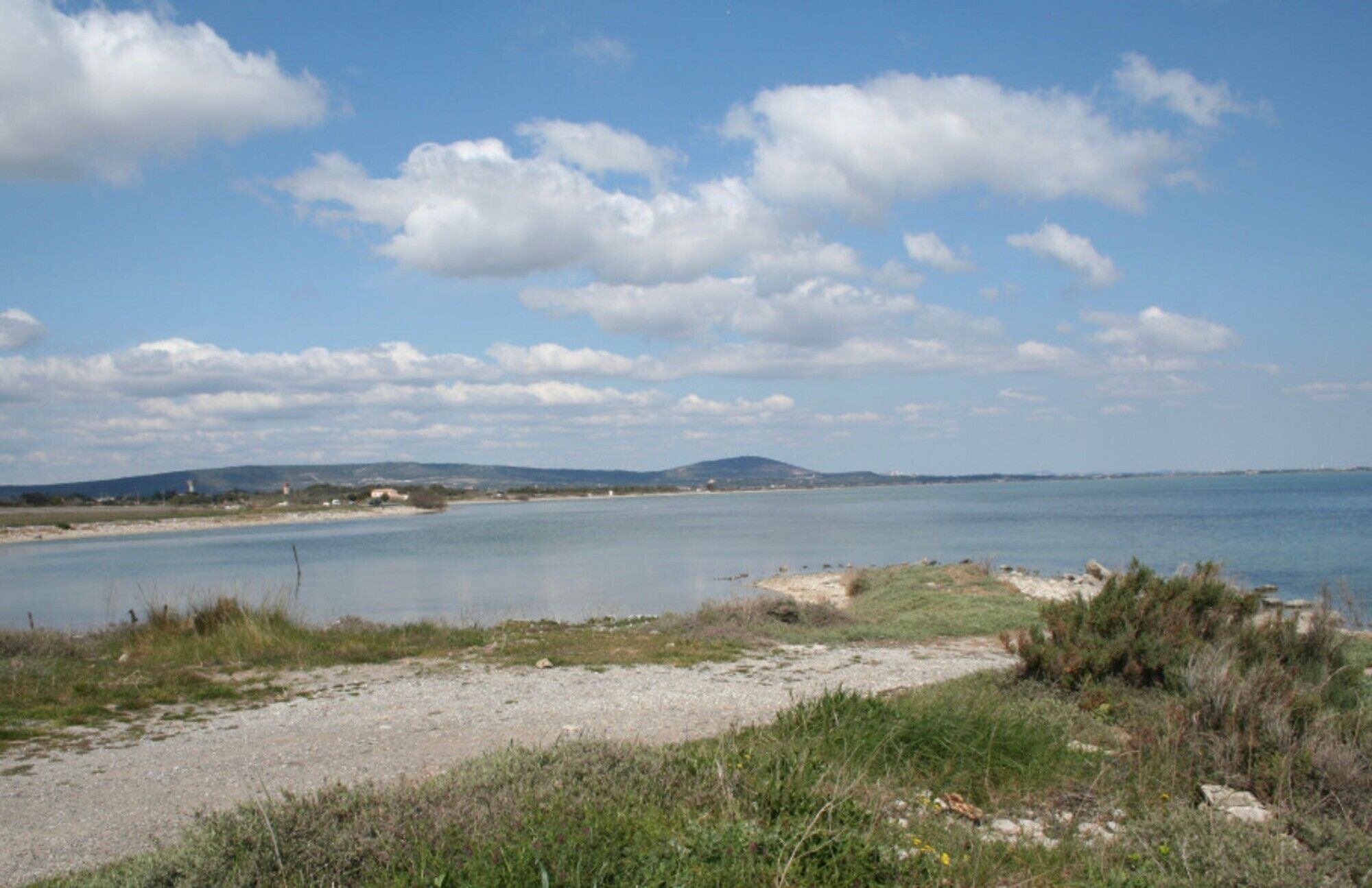 Een kustlandschap met heldere lucht, een zandstrand en een kalme zee.