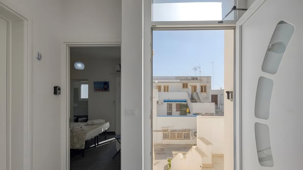 Un apartamento moderno con balcón, cama, escritorio y vistas a edificios vecinos.