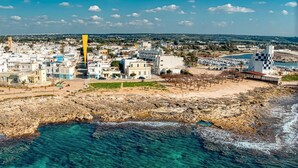 Un pueblo costero con edificios, una costa rocosa y agua azul cristalina.