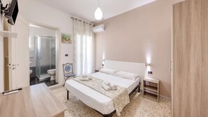 Ein Schlafzimmer mit Bett, Nachttischen, einem Schreibtisch und einer Dusche.