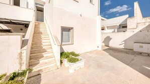 Ein modernes Gebäude mit einer Treppe, die zu einer Tür und einem kleinen Fenster mit weißer Fassade führt.
