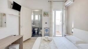 A hotel room with a bed, a desk, a television, a bathroom, and a sliding door to the outside. - Apartment 'Grande Struttura - Matrimoniale 6' with Balcony, Wi-Fi and Air Conditioning (Torre San Giovanni)