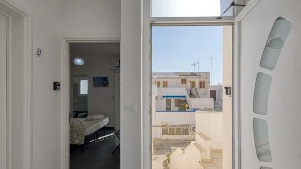 A hotel room with a bed, a small table, a window, and a door leading to a balcony. - Apartment 'Grande Struttura - Matrimoniale 6' with Balcony, Wi-Fi and Air Conditioning (Torre San Giovanni)