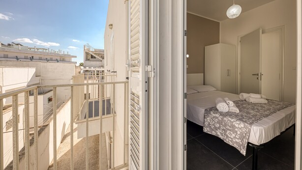 A hotel room with a bed, a bathroom, and a balcony. - Apartment 'Grande Struttura - Matrimoniale 1' with Balcony, Wi-Fi and Air Conditioning (Torre San Giovanni)