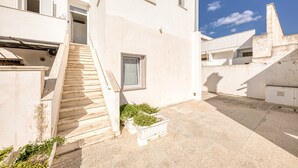 A building with a staircase leading to a door, a small window, and a white planter with plants. - Apartment 'Grande Struttura - Matrimoniale 1' with Balcony, Wi-Fi and Air Conditioning (Torre San Giovanni)
