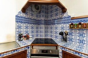 A kitchen with blue and white patterned tiles, a stove, and a spice rack.