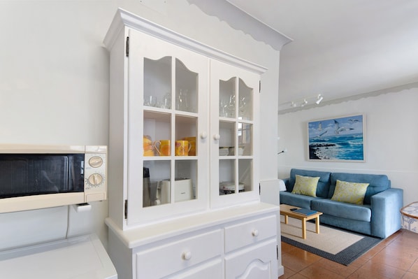A living room with a white cabinet, a blue sofa, and a painting on the wall.