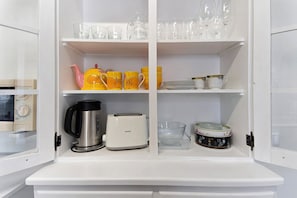A kitchen with white cabinets, a coffee maker, a toaster, and various dishes and cups.