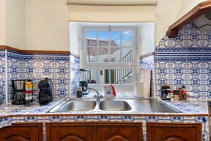A kitchen with a double sink, a window, and a tiled backsplash.