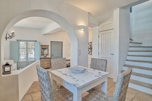 Un comedor con una mesa y sillas blancas, un espejo y una escalera.