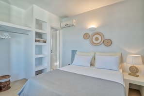 Een slaapkamer met een bed, een garderobe, een wandairconditioner en decoratieve muurkunst.
