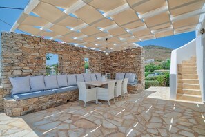 A stone-walled outdoor seating area with a pergola, stone flooring, and a view of the surrounding landscape. - Villa 'Afroditi A' with Sea View, Wi-Fi and Air Conditioning (Antiparos Town)