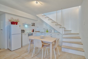 A compact kitchen with a dining area, a built-in oven, a microwave, and a sink. - Villa 'Afroditi B' with Sea View, Wi-Fi and Air Conditioning (Antiparos Town)