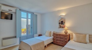 A bedroom with a bed, a dresser, a TV, and a window with a view. - Villa 'Afroditi B' with Sea View, Wi-Fi and Air Conditioning (Antiparos Town)