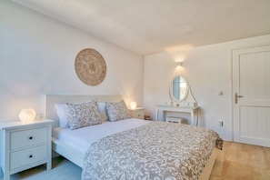 A bedroom with a bed, bedside tables, a dresser, a mirror, and a door. - Villa 'Afroditi B' with Sea View, Wi-Fi and Air Conditioning (Antiparos Town)