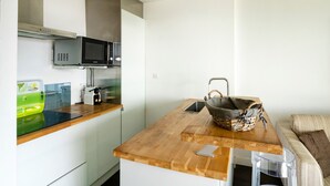 Una cucina compatta con forno a microonde, tostapane e piano di lavoro in legno.
