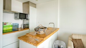 Una cucina compatta con forno a microonde, tostapane e un piano di lavoro in legno.