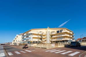 A multi-story building with balconies, a pedestrian crossing, and a parked vehicle. - Grand Large Studio Apartment – Ocean View, Perfect for a Getaway in Capbreton (Capbreton)