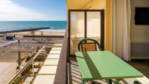 Un balcone con vista sulla spiaggia, un tavolo e una sedia.
