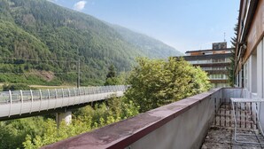 A balcony with a metal railing overlooking a forested hillside and a bridge. - Apartment 'Marilleva 900 Kristall' with Mountain View, Shared Terrace and Wi-Fi (Mezzana)