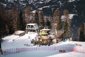 Une station de ski dotée d’une station de télésiège, d’un espace de repos couvert et d’un bâtiment avec un toit en pente.