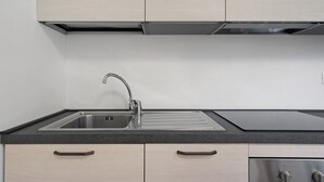 A kitchen with a stainless steel sink, a black countertop, and light-colored cabinets. - Apartment 'Marilleva 900 Kristall' with Mountain View, Shared Terrace and Wi-Fi (Mezzana)