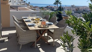 En terrasse med et spisebord, der udover et kystlandskab.