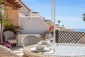 A dining area with wicker furniture, a glass table, and a view of the sea. - Holiday Home 'Cecilia' with Sea View, Wi-Fi and Air Conditioning (Nerja)