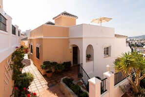 A residential building with a tiled patio, potted plants, and a balcony with an umbrella. - Holiday Home 'Cecilia' with Sea View, Wi-Fi and Air Conditioning (Nerja)