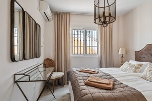 A bedroom with a bed, bedside table, chair, and a window with curtains. - Holiday Home 'Cecilia' with Sea View, Wi-Fi and Air Conditioning (Nerja)