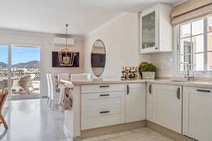 A modern kitchen with white cabinets, a large mirror, and a view of the city. - Holiday Home 'Cecilia' with Sea View, Wi-Fi and Air Conditioning (Nerja)