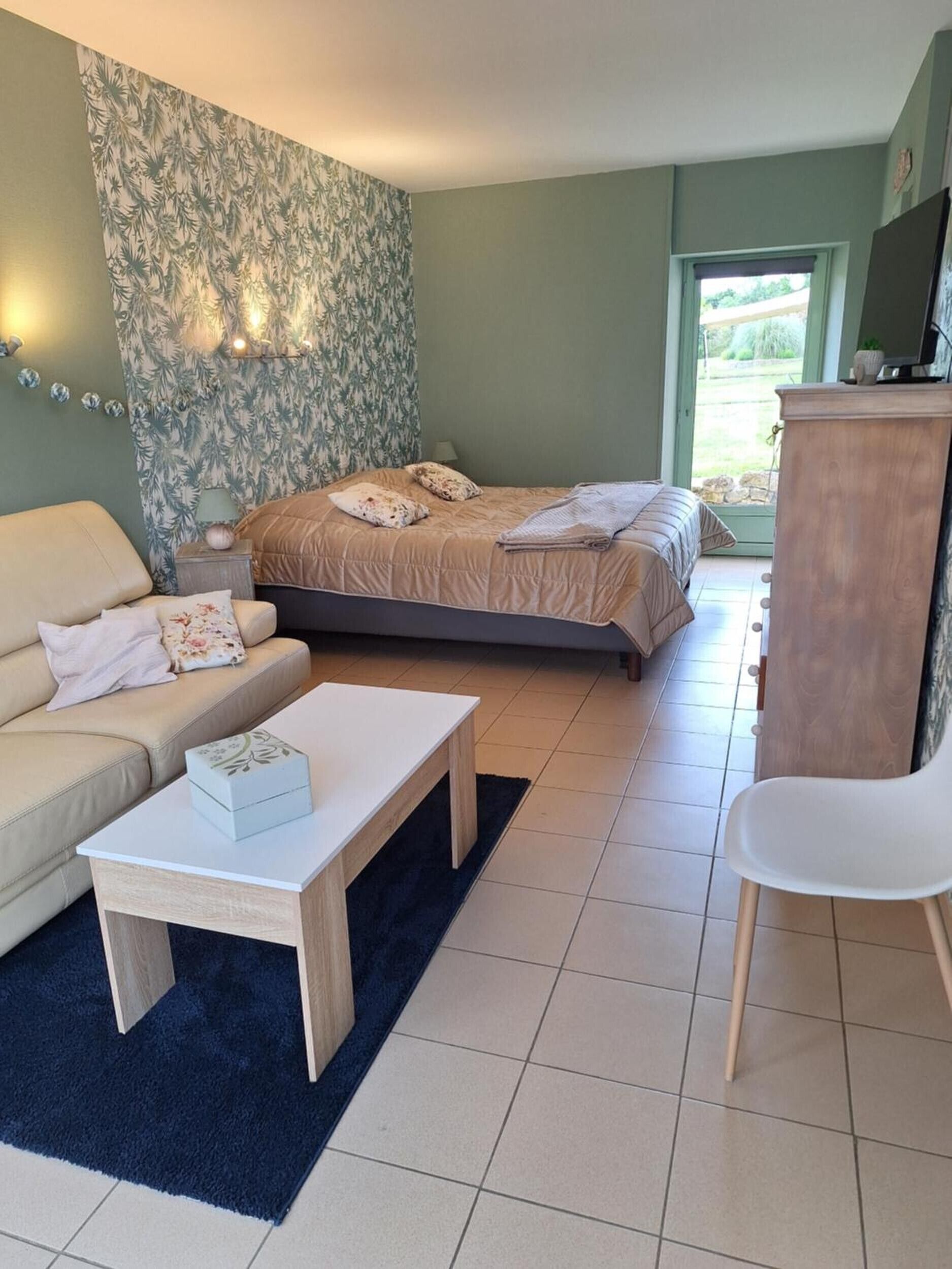Un dormitorio con cama, sofá, mesa de centro, sillón y mueble para televisor.