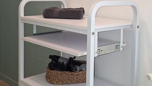 Un chariot en métal blanc, doté d’étagères, d’un panier et d’une serviette.